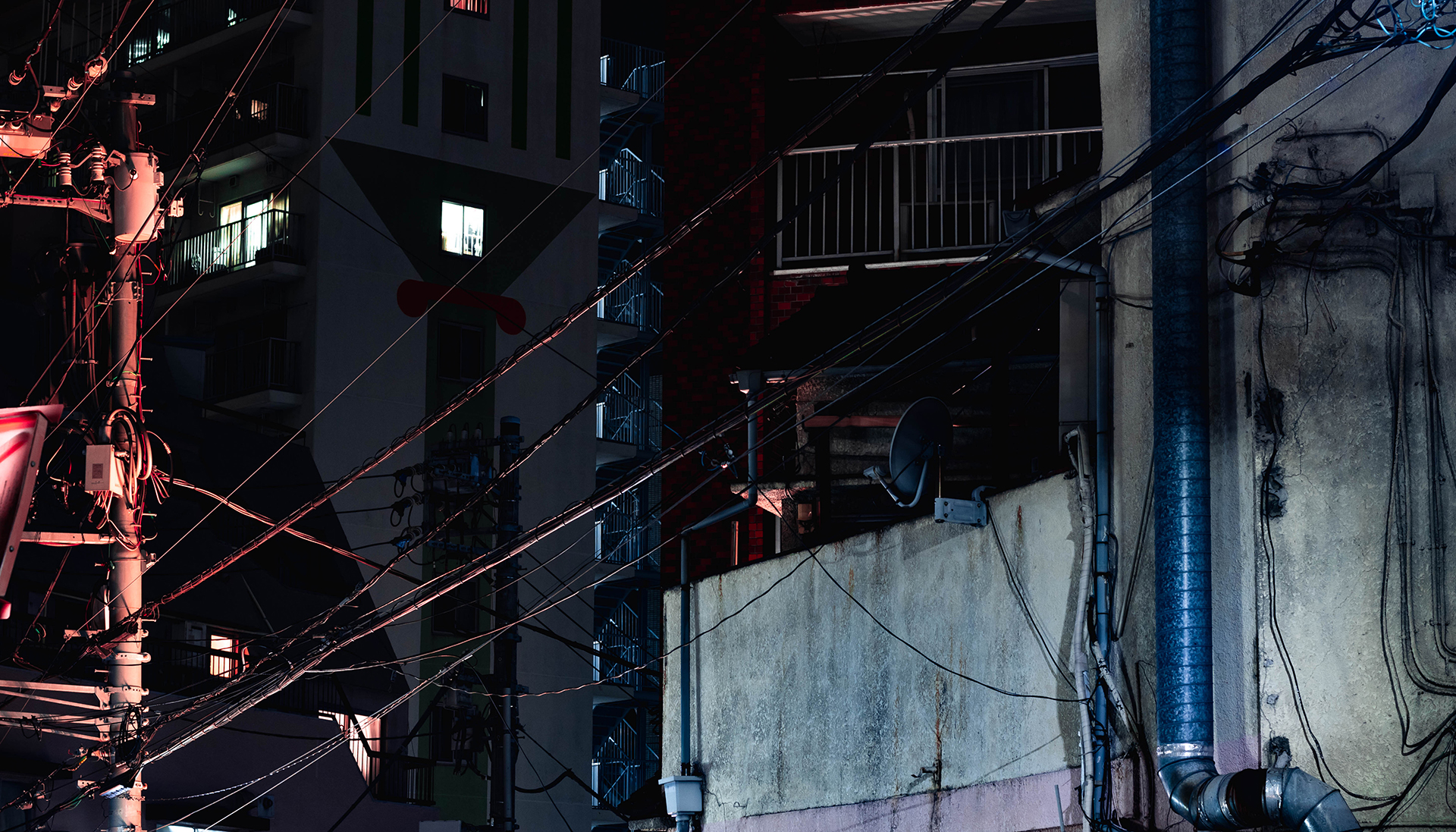 Chaotic frame of power poles, wires, and snippets of concrete building facades.